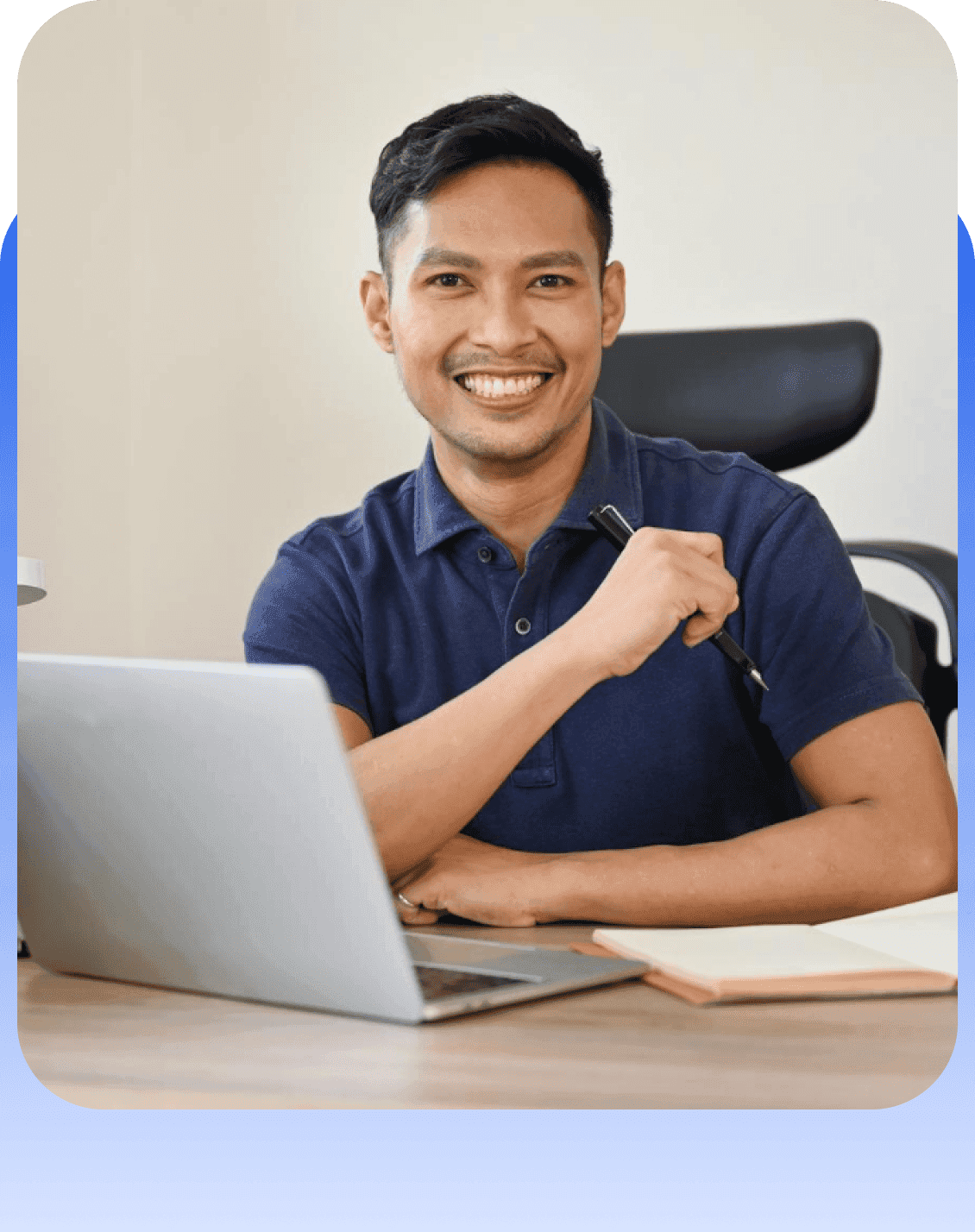 Offshore professional smiling at desk with laptop and notebook