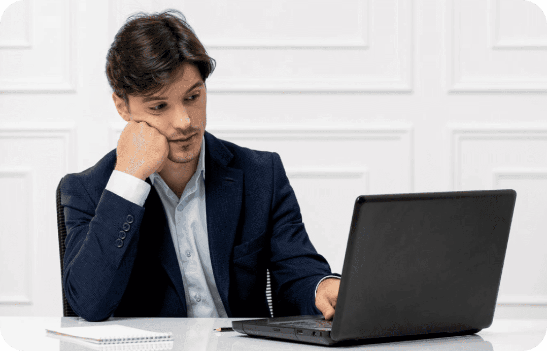 Business owner thinking at desk with laptop